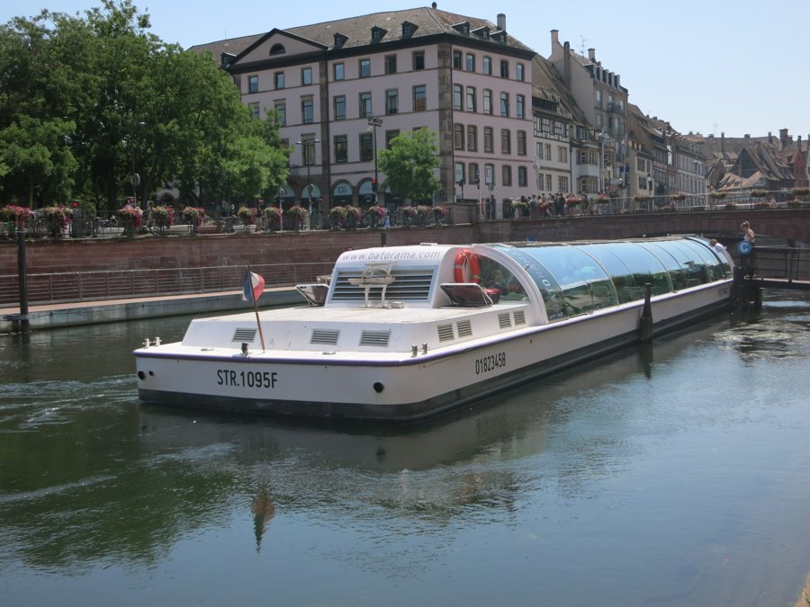 Batorama-Ausflugsboot auf einem Kanal in Strasbourg, Fahrräder am blumengeschmückten Ufer.