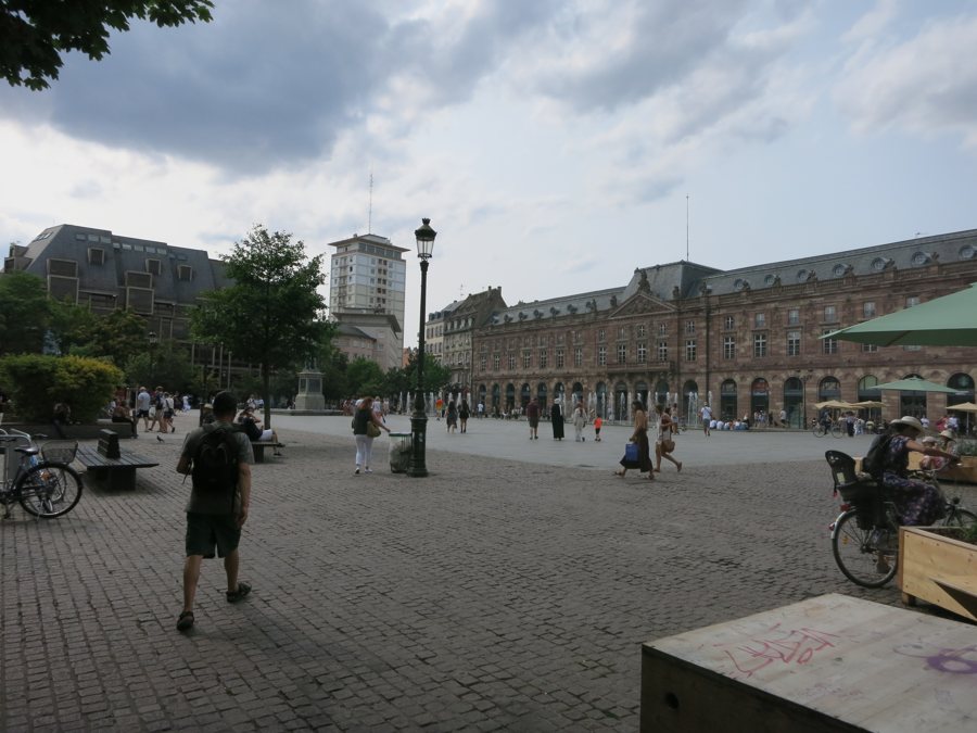 Fußgänger auf dem gepflasterten Place Kléber vor der historischen Aubette in Straßburg.